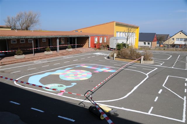 Weiße Linien auf dem dunkelgrau asphaltierten Schulhof stellen ein symbolisches Strassennetz dar.