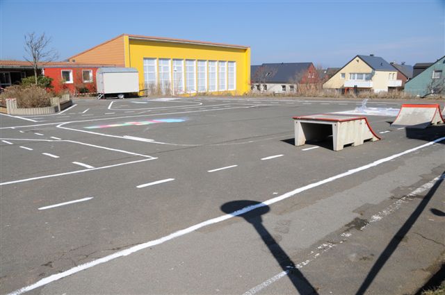 Weiße Linien auf dem dunkelgrau asphaltierten Schulhof stellen ein symbolisches Strassennetz dar.