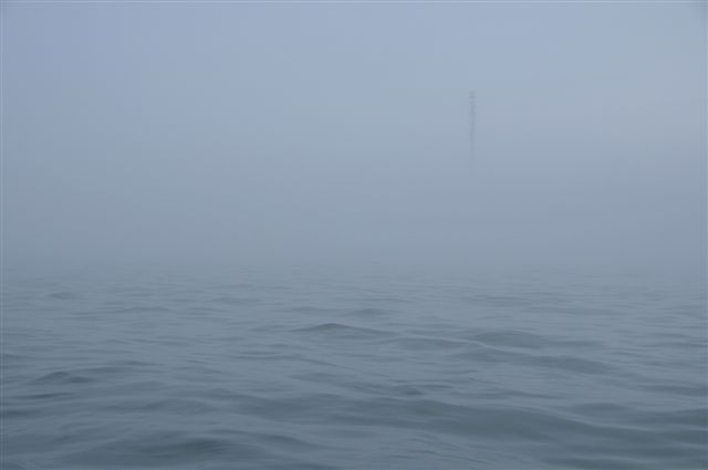 Sehr dichter Nebel bei Helgoland vom Boot auf dem Wasser aus fotografiert. Man kann eben gerade mal 200 Meter weit gucken und gerade erst zeichnet sich schemenhaft der Telekommast auf Helgolands Oberland in der trüben Sicht ab.