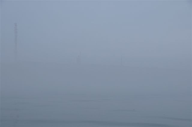 Sehr dichter Nebel bei Helgoland vom Boot auf dem Wasser aus fotografiert. Man kann eben gerade mal 200 Meter weit gucken und schemenhaft zeichnen sich die drei großen Türme Helgolands durch den Nebel ab: Der Telekommast, der Kirchturm und der Schornstein des Kraftwerks.