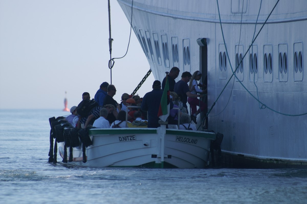 Ein Börteboot hat längsseits eines Passagierschiffes festgemacht und bringt die Gäste wieder an Bord.