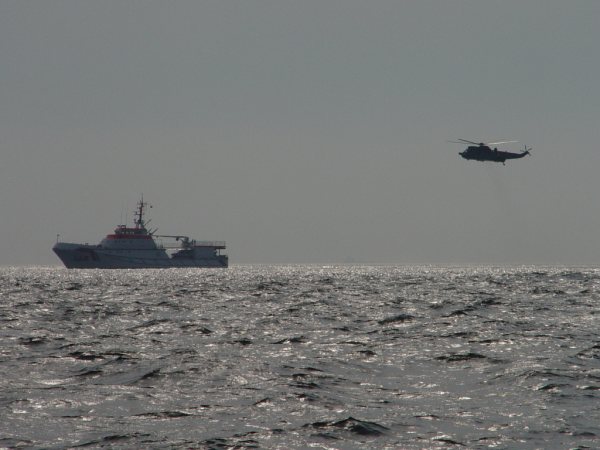 Der Seenotrettungskreuzer Hermann Marwede und ein Hubschrauber proben auf See die Übernahme von Personen.