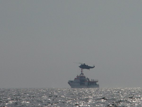 Der Seenotrettungskreuzer Hermann Marwede und ein Hubschrauber proben auf See die Übernahme von Personen.
