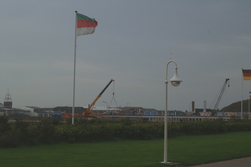 Von der Landungsbrücke aus sieht man einen großen Kran, der die Helgoländer Dünenfähre Witte Kliff im Scheibenhafen am Haken hat.