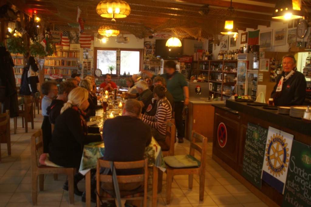 Im Dünenrestaurant auf der Helgoländer Düne sitzen an einer langen Tafel die Freunde von Lutz Hardersen und feiern den Saisonabschluss.