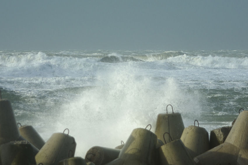 Bild zwischen die Tetrapoden an Helgolands Kringel hindurch in das wild tosende Meer.