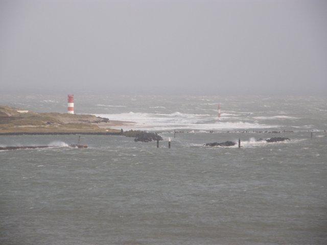 Blick von der Helgoländer Haupttreppe im Oberland hinüber zum Südstrand der Düne mit dem rotweißen Leuchtturm "Oberfeuer Düne". Auch hier reicht das Meer schon sehr weit den Strand hinauf.