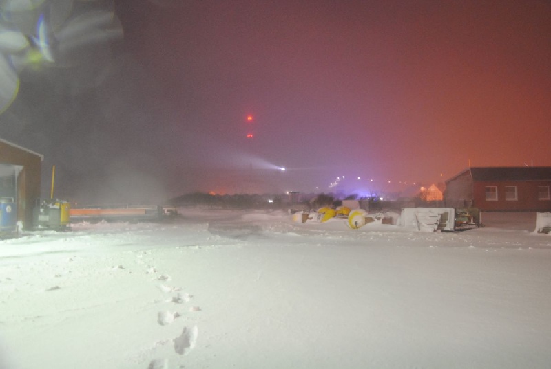 Der Helgoländer Leuchtturm strahlt im Schneetreiben die Schneeflocken an, so dass der Leuchtturmstarhl gut sichtbar wird.