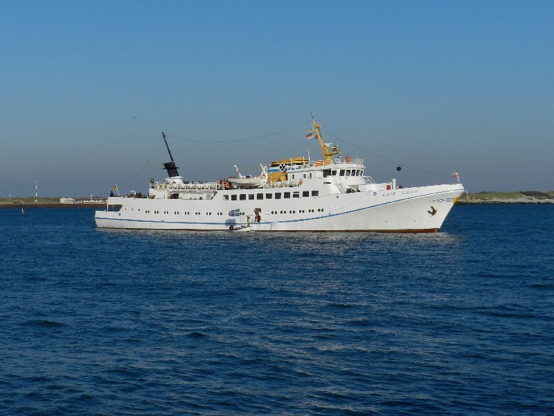 Das Passagierschiff Fair Lady auf der Helgoländer Reede wird zum letzten Mal in dieser Saison eingebootet, dazu liegt gerade das letzte Boot an der Helgoland-Pforte der Steuerbordseite.