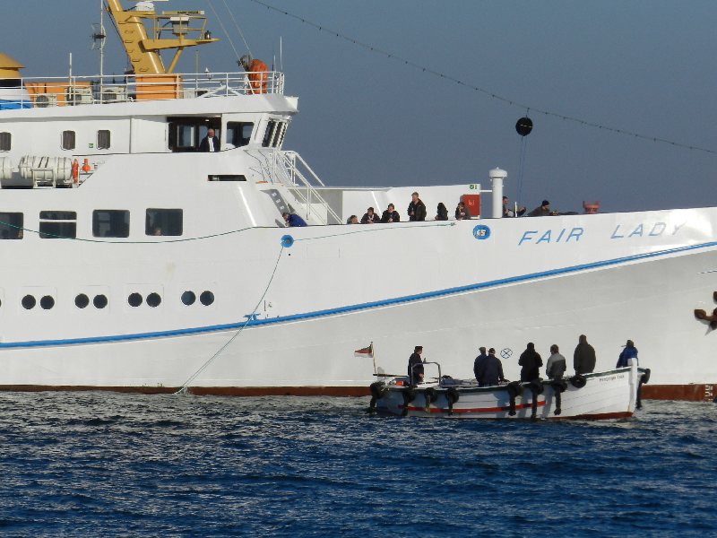 Das Passagierschiff Fair Lady auf der Helgoländer Reede wird zum letzten Mal in dieser Saison eingebootet, dazu liegt gerade das letzte Boot an der Helgoland-Pforte der Steuerbordseite.