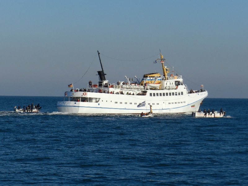 Das Passagierschiff Fair Lady auf der Helgoländer Reede wird zum letzten Mal in dieser Saison eingebootet, dazu liegt gerade das letzte Boot an der Helgoland-Pforte der Steuerbordseite.