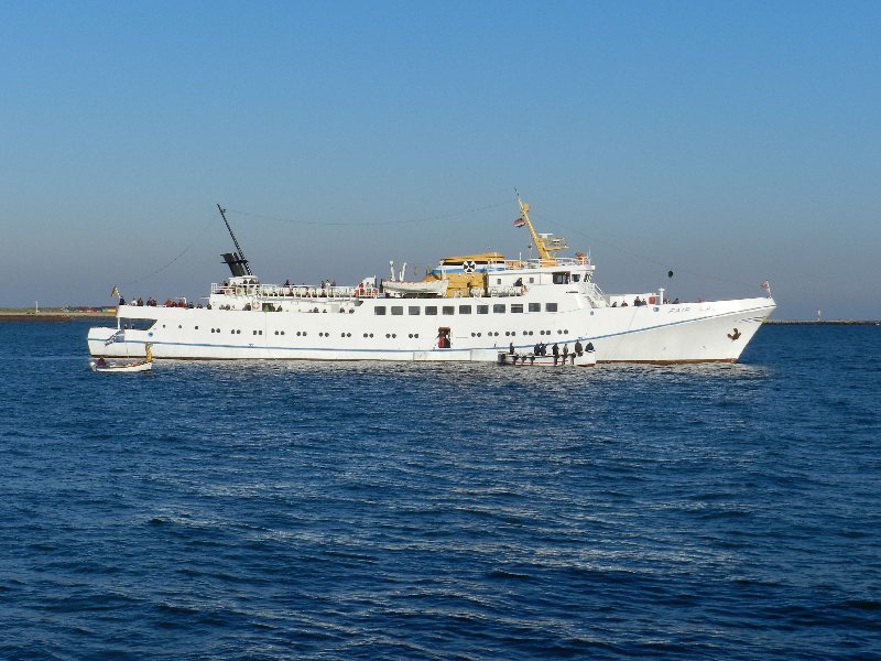 Das Passagierschiff Fair Lady auf der Helgoländer Reede wird zum letzten Mal in dieser Saison eingebootet, dazu liegt gerade das letzte Boot an der Helgoland-Pforte der Steuerbordseite.