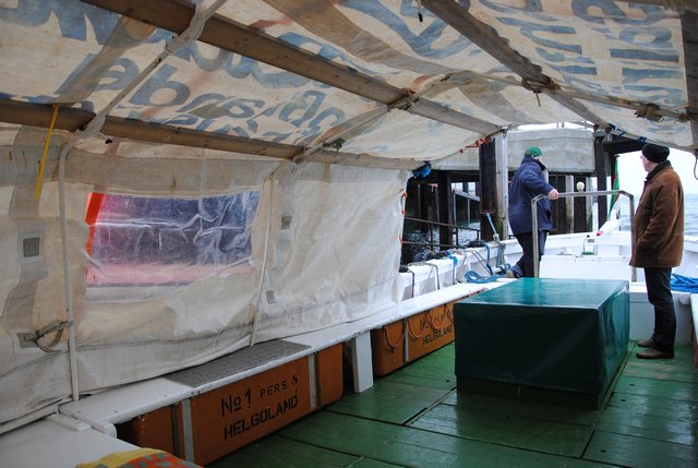 In einem Helgoländer Börteboot, das im Wintereinsatz als Dünenfähre eine Art Zeltaufbau als Wetterschutz hat.