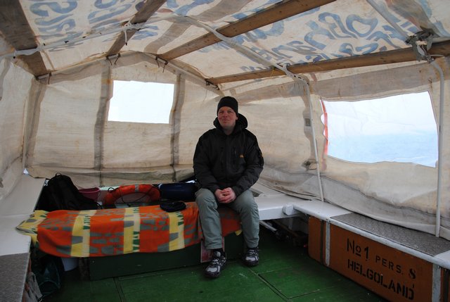 In einem Helgoländer Börteboot, das im Wintereinsatz als Dünenfähre eine Art Zeltaufbau als Wetterschutz hat.