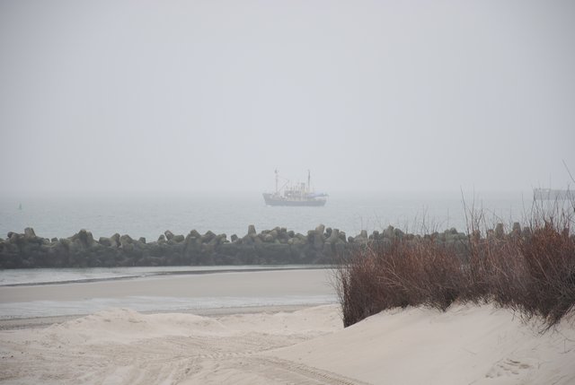 Ein Schiff zieht im Dunst an der Helgoländer Düne vorbei