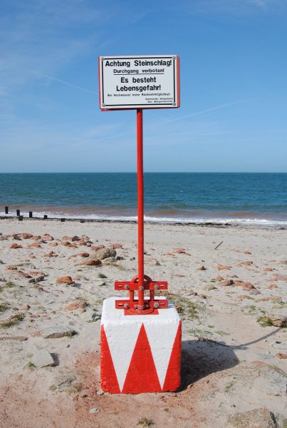 Warnschild vor lebensgährlichem Steinschlag direkt am Fels am Nordstrand.