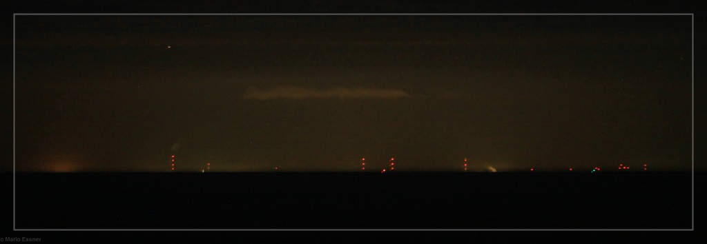 Nachtaufnahme von Helgoland aus Richtung Süden und  bei klarer Sicht. Die roten Warnlichter der Türme am Festland sind zu sehen.