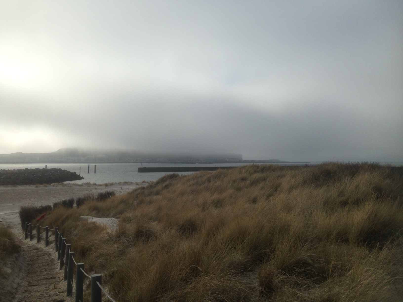 von der Düne aus gesehen ist Helgoland im Hintergrund und von Norden schiebt sich Seenebel zwischen Helgoland und Düne.