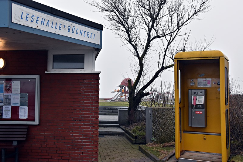 Die arg ramponierte alte, gelbe Telefonzelle (ohne Tür) bei der Lesehalle auf Helgoland.
