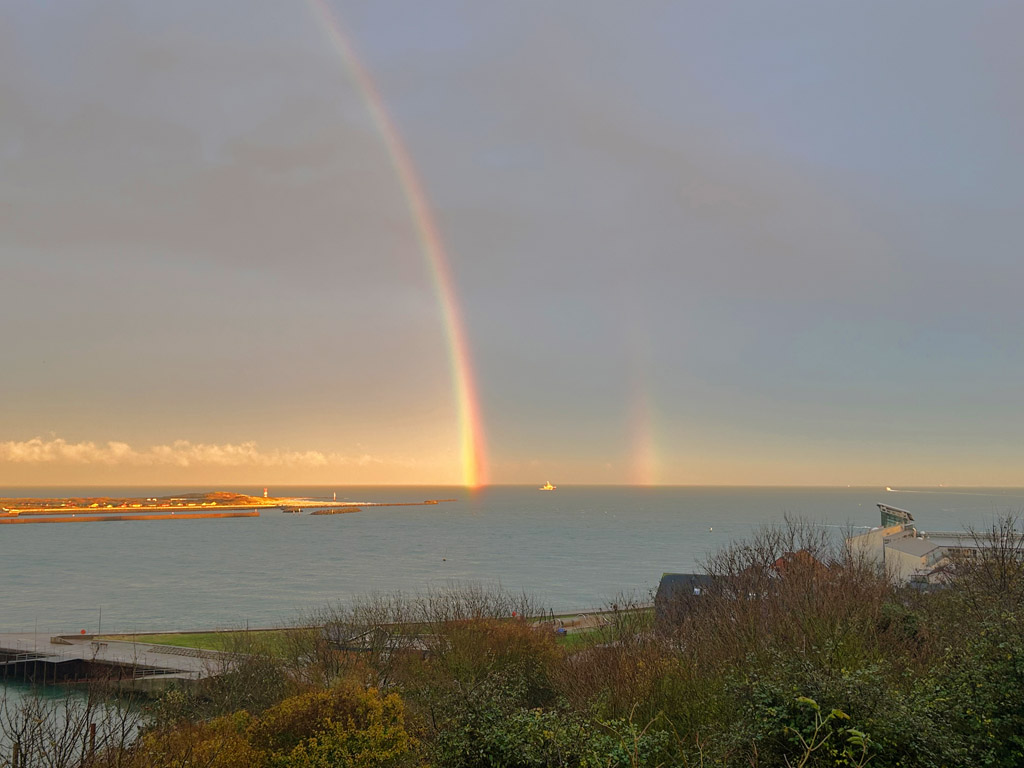 Regenbogen mit Nebenbogenfragment am Spätnachmittag über der Düne vom Falm auf Helgoland aus gesehen.