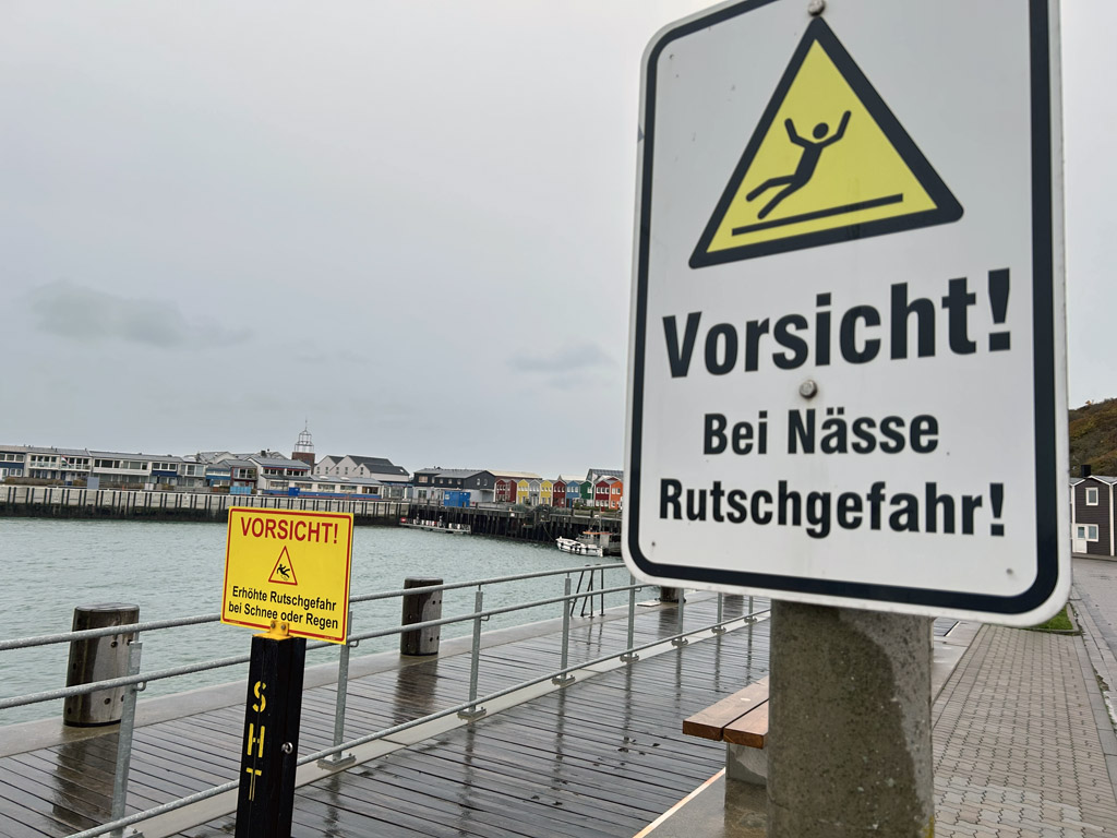Zwei Warnschilder vor Glätte am Nordzugang zum Holzbohlenweg am Scheibenhafen.