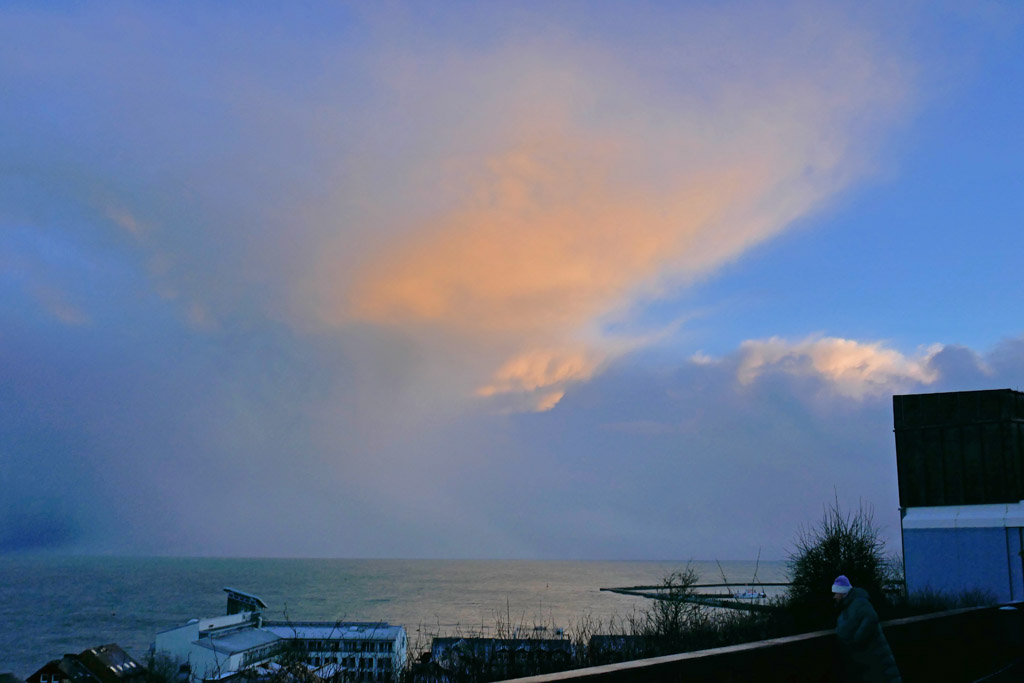 Eine Wolke über dem Südhimmel erscheint durch die untergehende Sonne rosa.