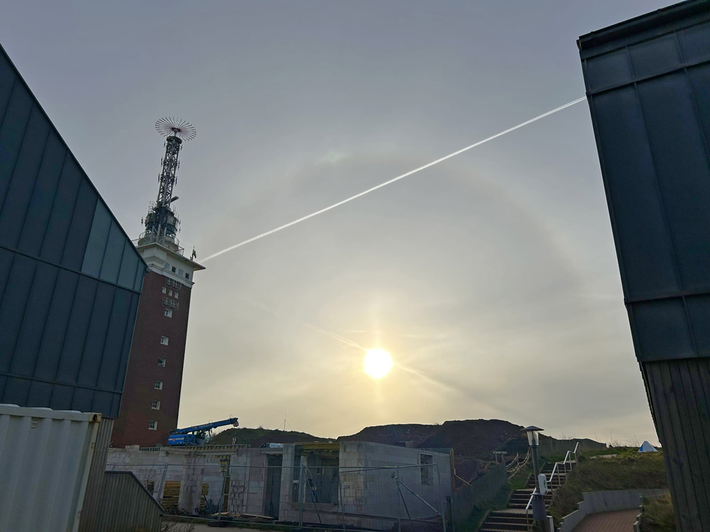 Ein Halo an Helgolands Westhimmel mit dem Leuchtturm im Oberland im Vordergrund.