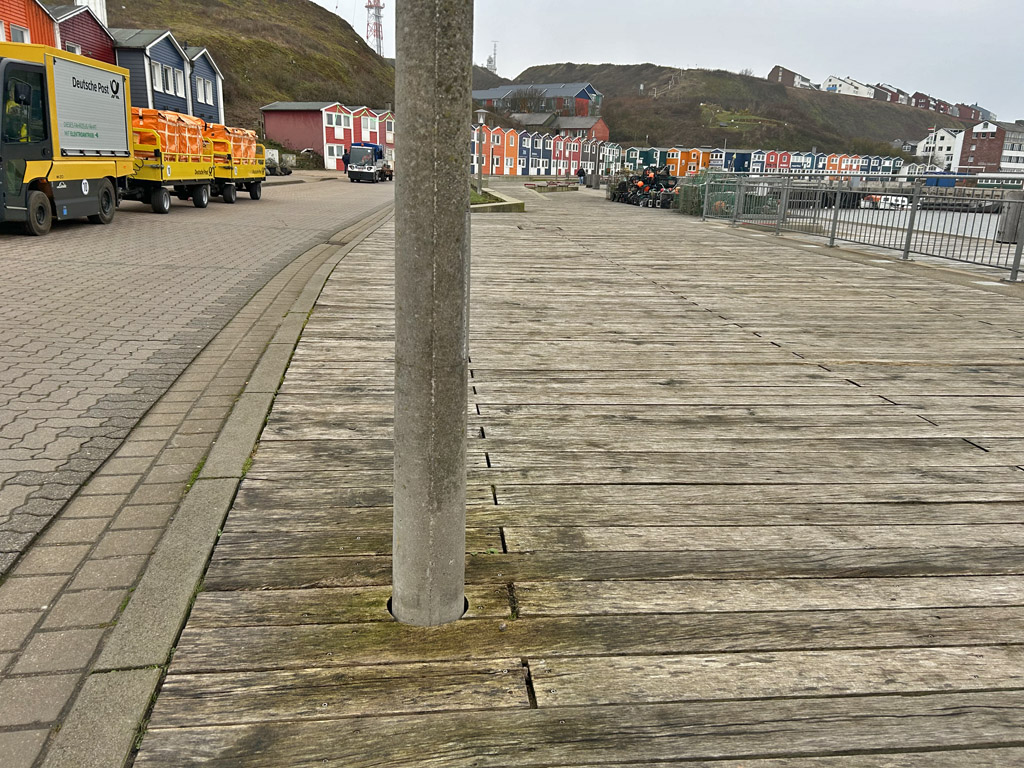 Gelbbraune Verf&auml;rbung von Eichenholzbohlen rund um einen Laternenpfahl am Scheibenafen auf Helgoland.