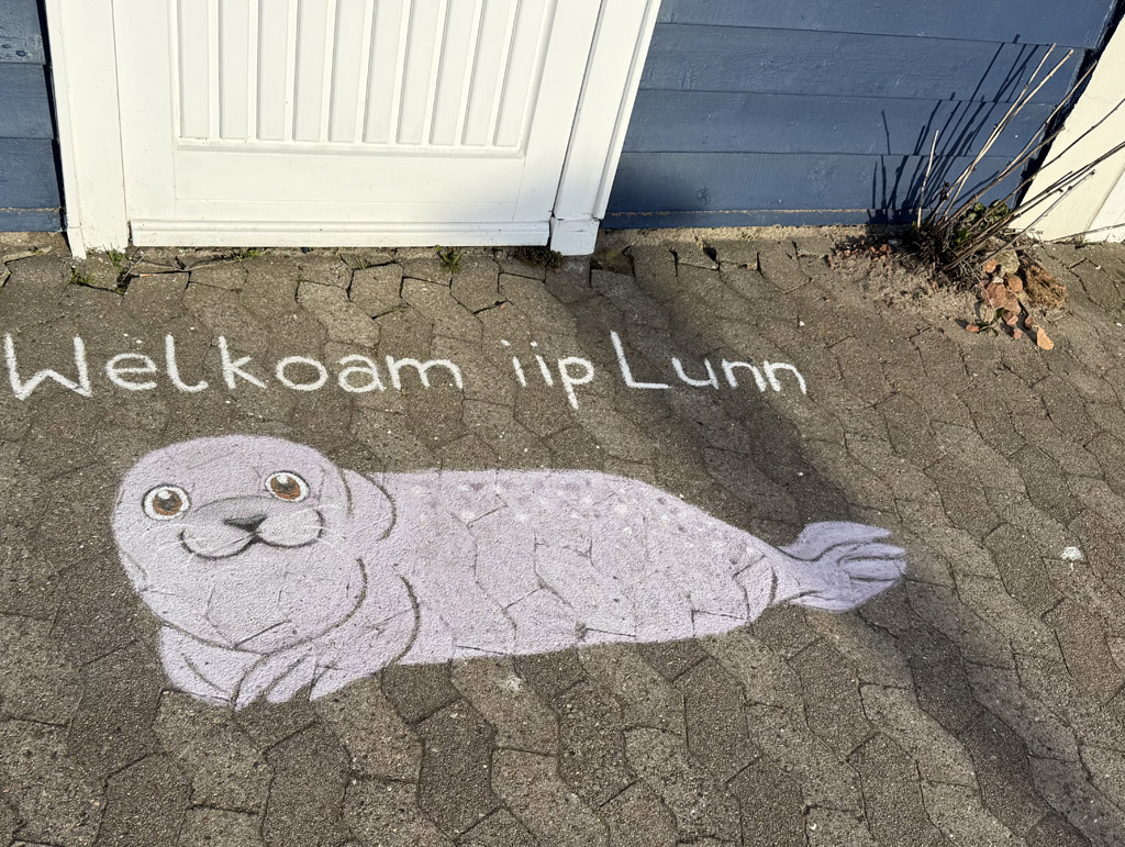 Ein Seehund als Stra&szlig;enmalerei vor einer Hummerbude auf Helgoland mit dem Schriftzug auf helgol&auml;ndisch Welkoam iip Lun.