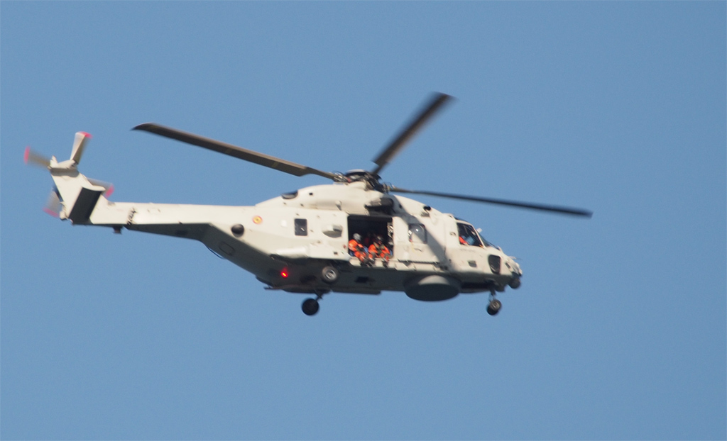 Spanischer NH90 Hubschrauber &uuml;be der Reede Helgolands, Besatzungsmitglieder lassen aus der offenen T&uuml;r die Beine baumeln .