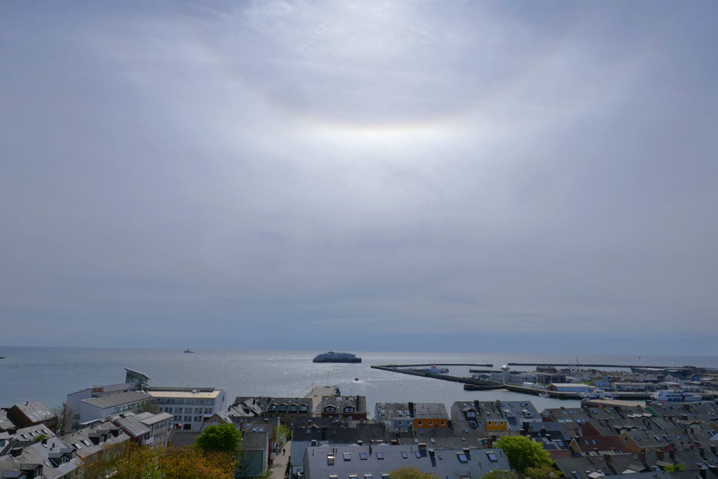 Die Fridtjof Nansen vor Anker auf Helgolands S&uuml;dreede mit einem Teil eines 22 Grad Halos hoch &uuml;ber ihr in den Wolken.