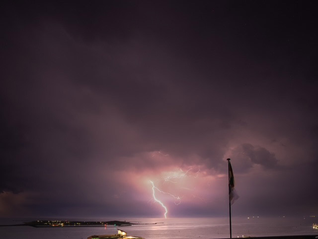 In der Nacht schl&auml;gt ein Blitz nicht weit hinter der D&uuml;ne in das Meer ein.