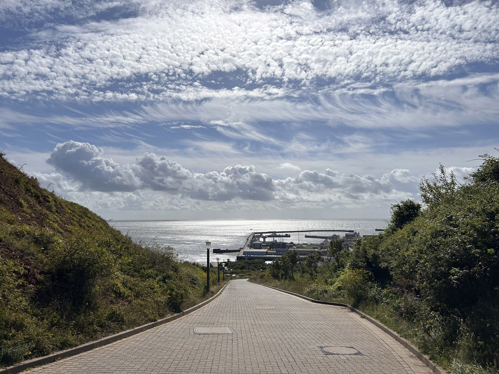 Blick von oben den Autoberg hinunter bis zum Horizont und mannigfaltigen Wolken am Himmel.