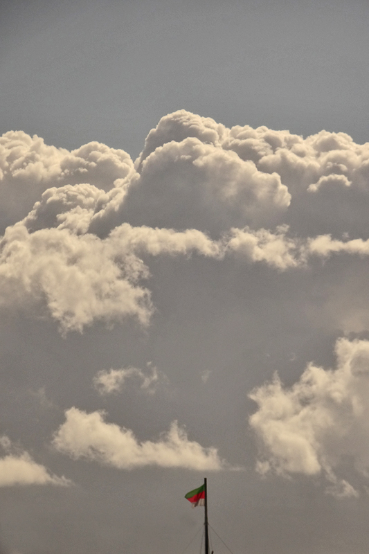 Am unteren Bildrand ist eine gr&uuml;nrotwei&szlig;e Helgolandflagge zu sehen, w&auml;hrend sich am Horizont gewaltige Wolken auft&uuml;rmen.