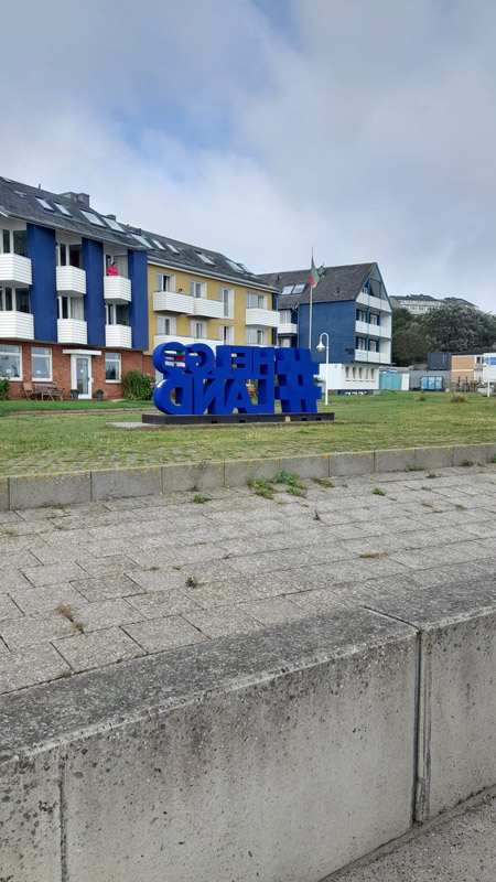 Ein Riesenschriftzug #Helgoland in blauen Buchstaben an der Kurpromenade.