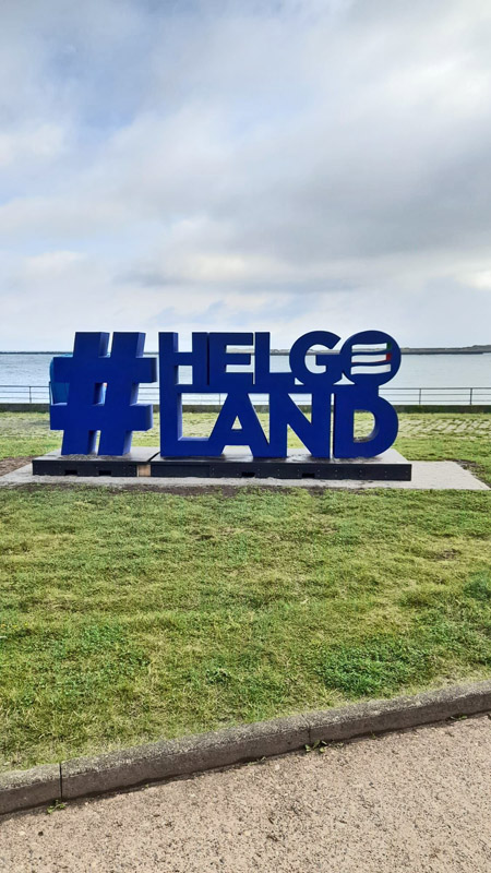 Ein Riesenschriftzug #Helgoland in blauen Buchstaben an der Kurpromenade.