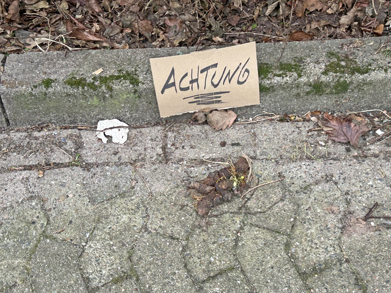 Ein Hundekothaufen auf Helgoland ist am Stra&szlig;enrand mit einem ACHTUNG-Schild markiert.