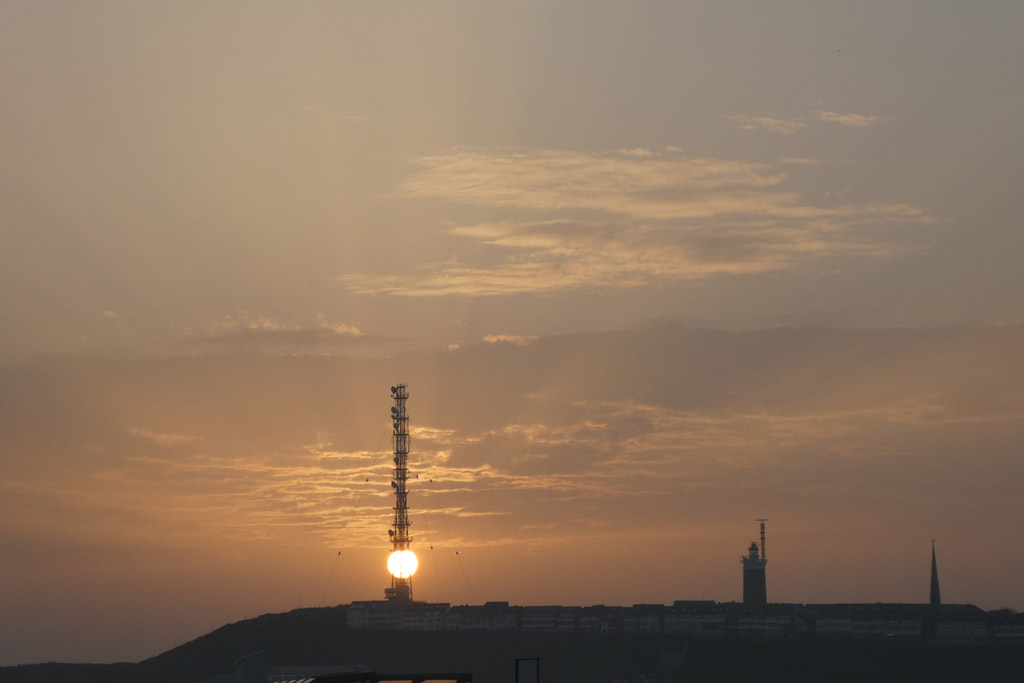 Die Sonne hinter dem Telekommast auf Helgoland von der D&uuml;ne aus gesehen.