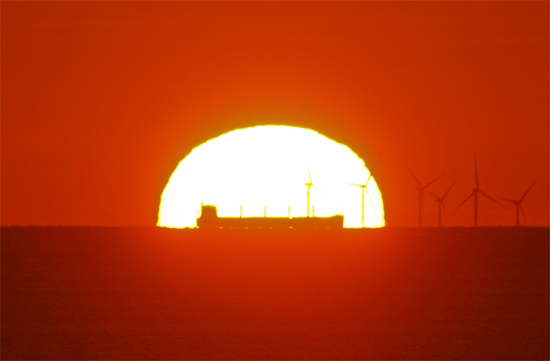 Sonnenuntergang hinter Windindustriegebiet Godee Wind 3 von Helgoland aus gesehen.