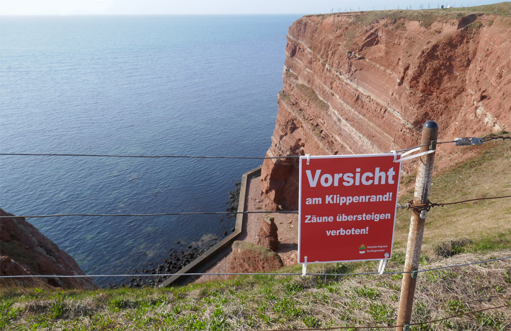 Gleich nach dem Zaun am Klippenrandweg geht es steil hinunter. Ein Warnschild verbietet das &Uuml;bersteigen des Zauns.