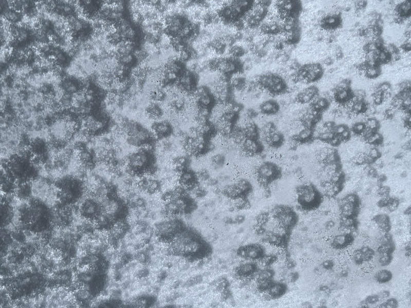 An einer Fensterscheibe backende Schneeflocken von innen fotografiert.